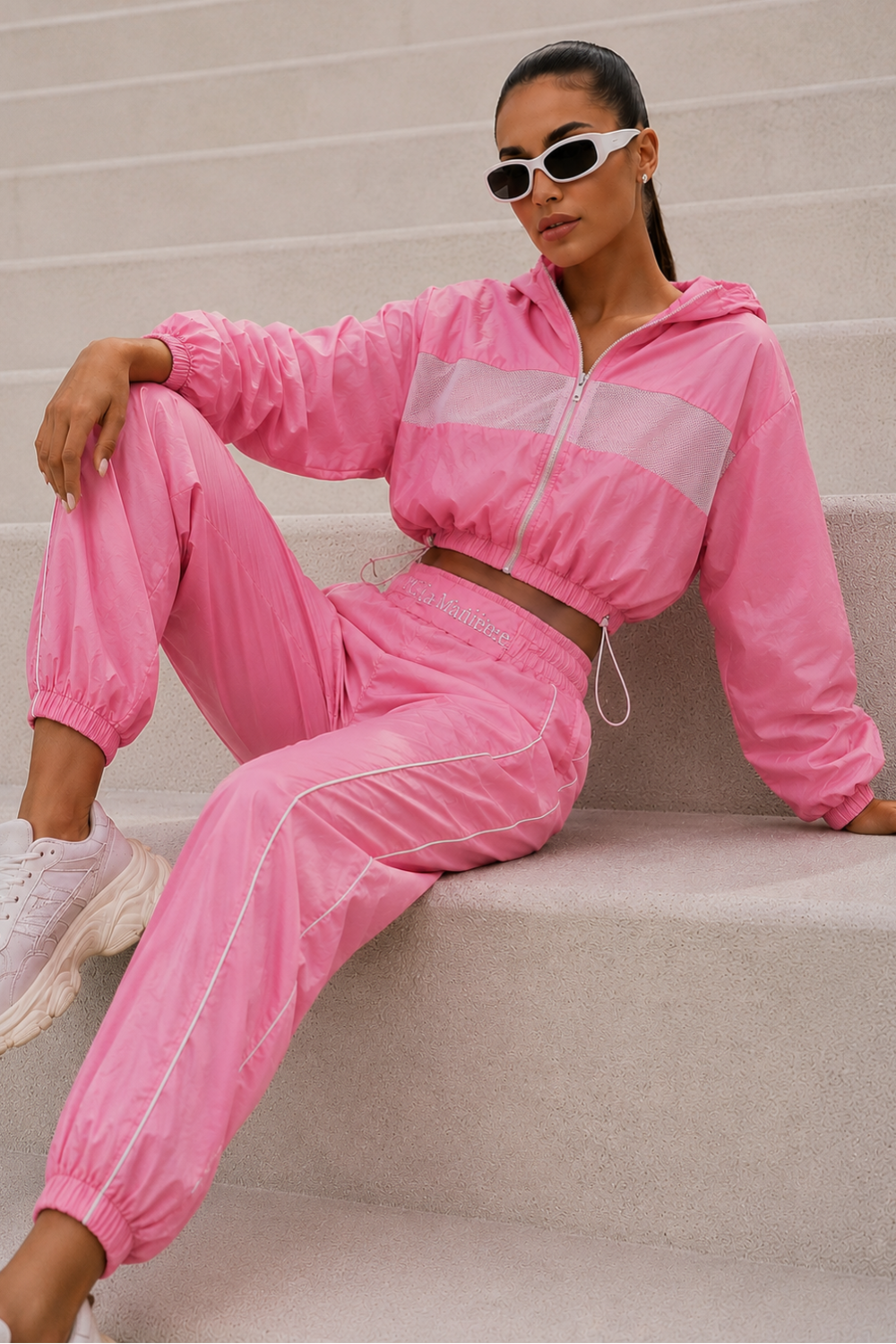 Person wearing a pink tracksuit sitting on stairs.